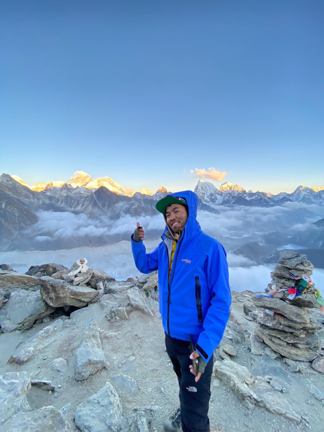 Dawa am frühen Morgen an einem Steinmal, er zeigt uns den Weg, dahinter die Bergkette im ersten Licht
