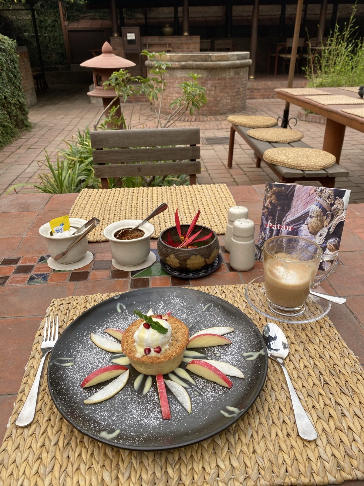 Ein gedeckter Tisch in einem Innenhof in Patan, Kaffee und Kuchen