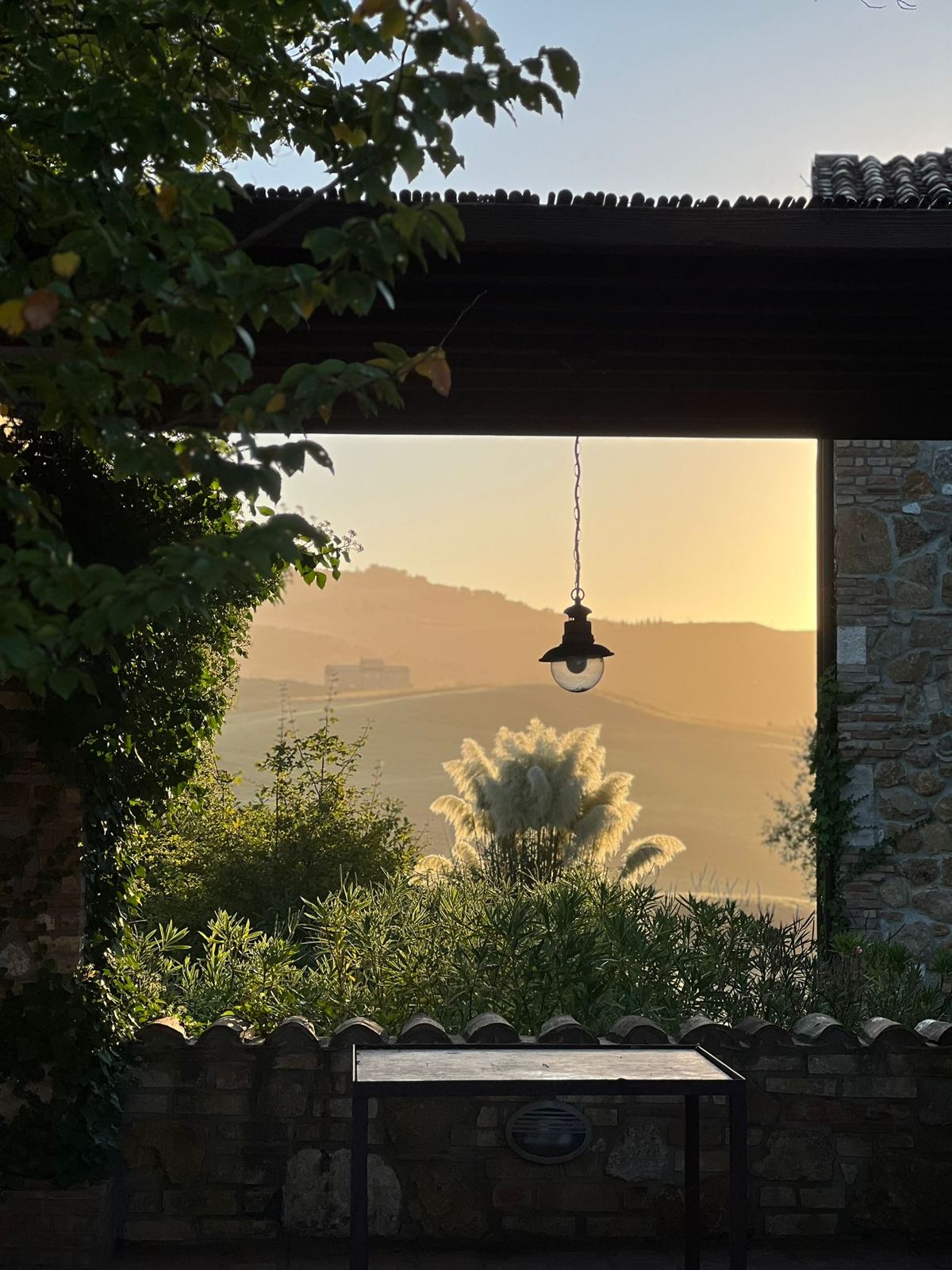Blick durch ein Holzfenster in die Hügellandschaft im Abendlicht